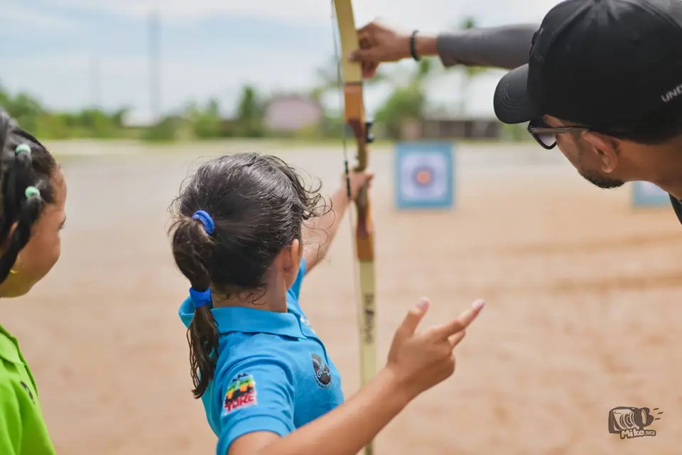 Coach helping an archer at the range